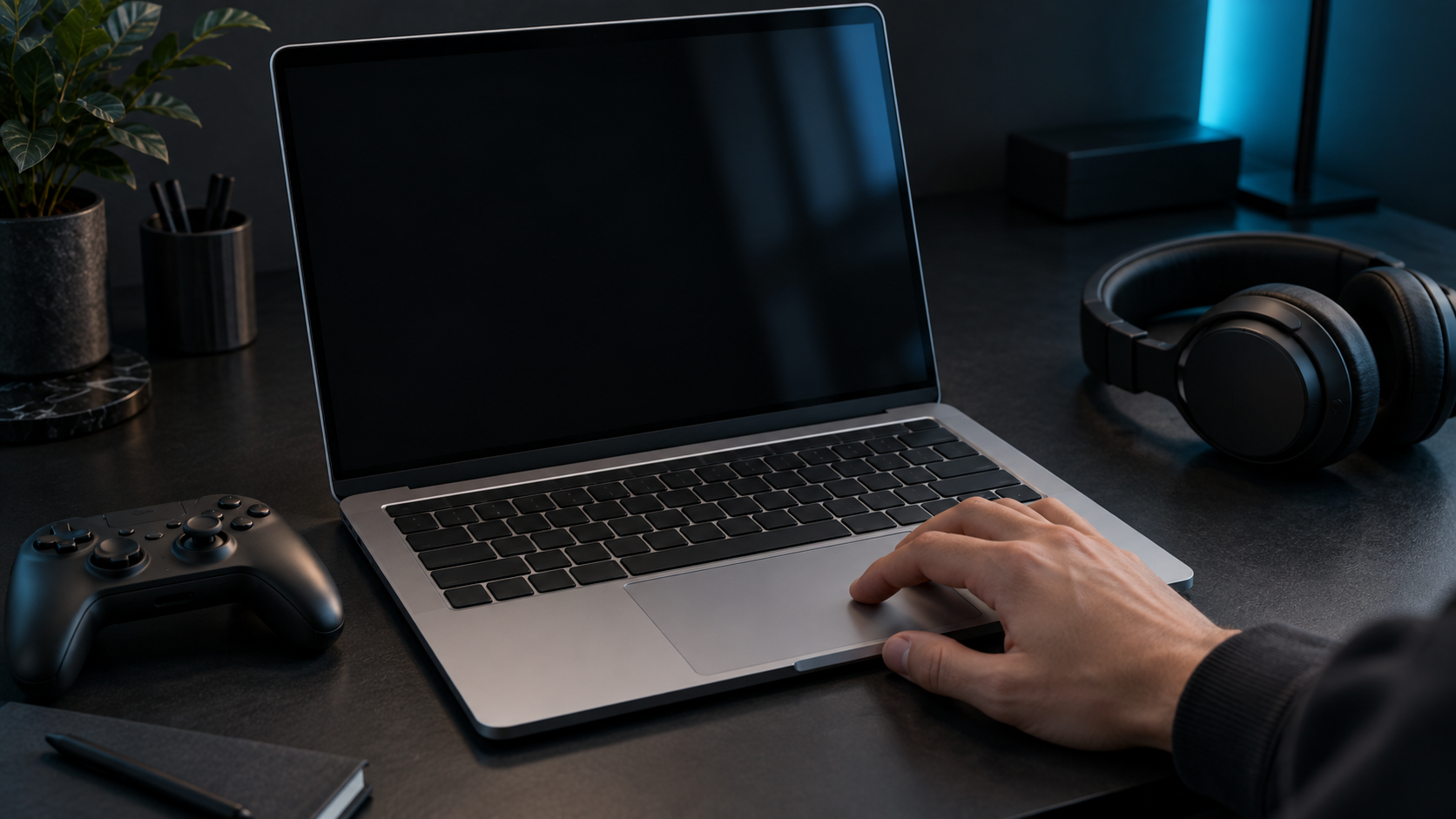 An unbranded Mac-style laptop with a blank display sits beside a game controller and headset